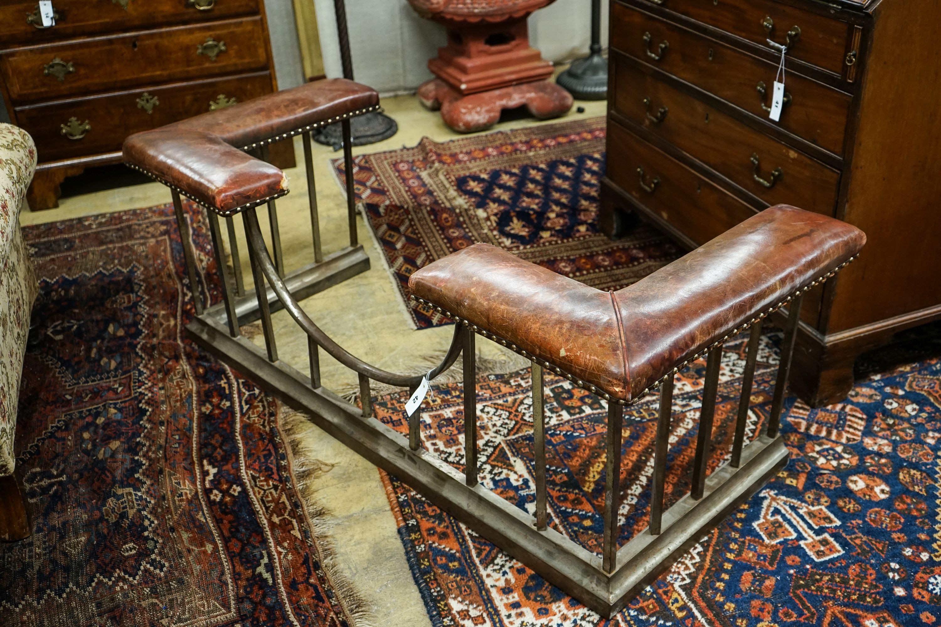 An early 20th century steel and burgundy leather club fender, length 140cm, depth 58cm, height 50cm